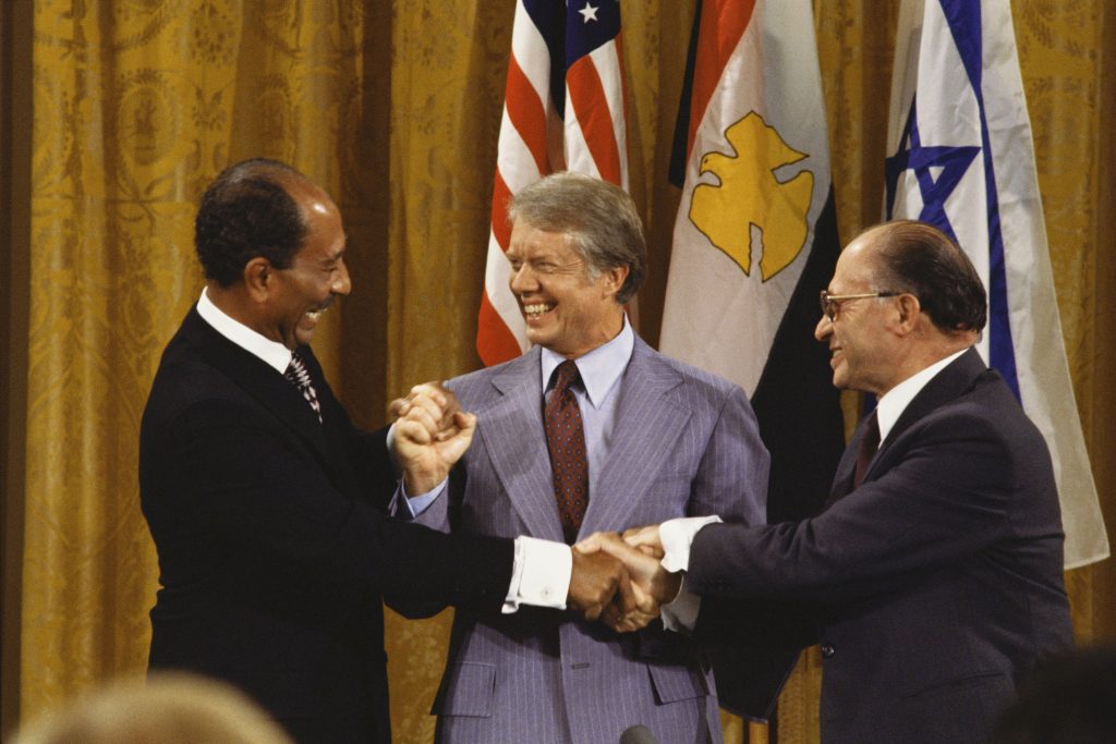 Jimmy Carter et al. standing next to a man in a suit and tie